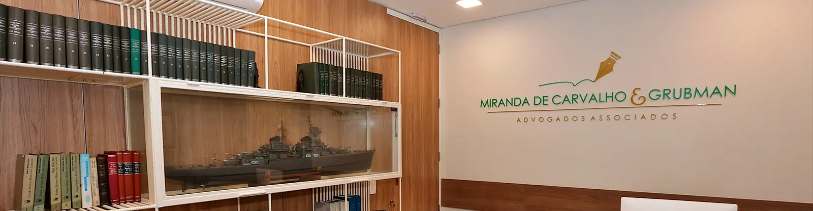 Maquete de navio na estante do escritório, ao lado do logotipo da sociedade