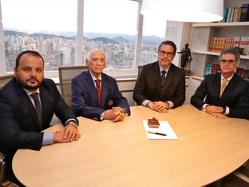 Os quatro sócios reunidos na sala de reuniões do escritório